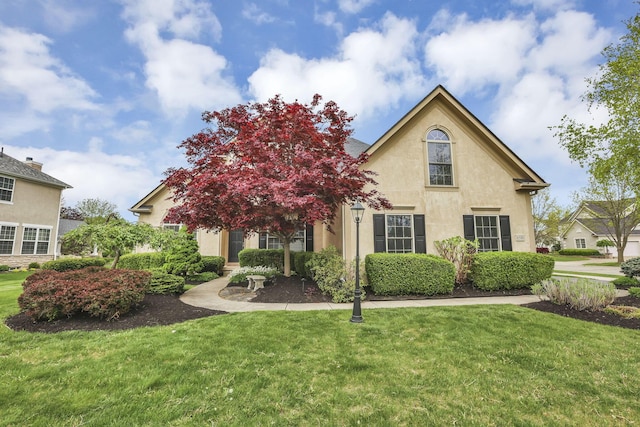 view of front of house with stucco siding and a front lawn