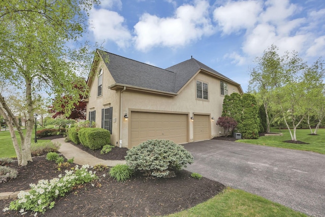 view of side of home with a garage, roof with shingles, stucco siding, and aphalt driveway