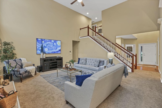 living area with carpet floors, a high ceiling, stairs, and ceiling fan