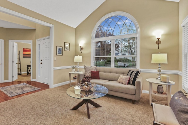 living area with baseboards, vaulted ceiling, and wood finished floors