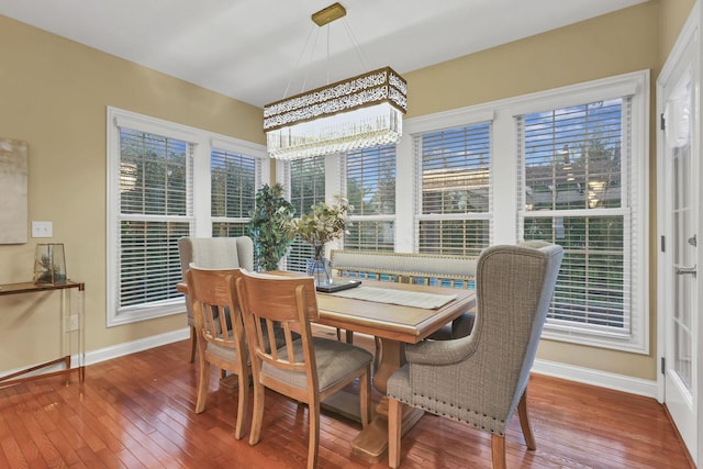 dining space with baseboards, an inviting chandelier, and hardwood / wood-style floors