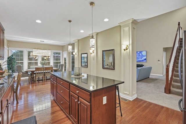 kitchen with a kitchen island, hanging light fixtures, a breakfast bar, and wood finished floors