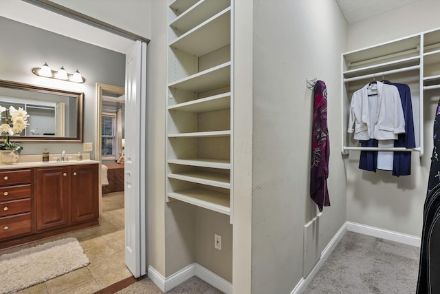 bathroom featuring baseboards, a spacious closet, tile patterned flooring, and vanity