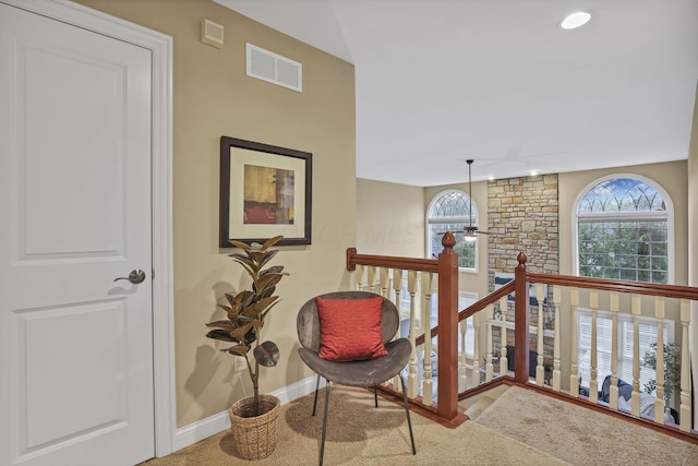 living area featuring baseboards, visible vents, a wealth of natural light, and an upstairs landing