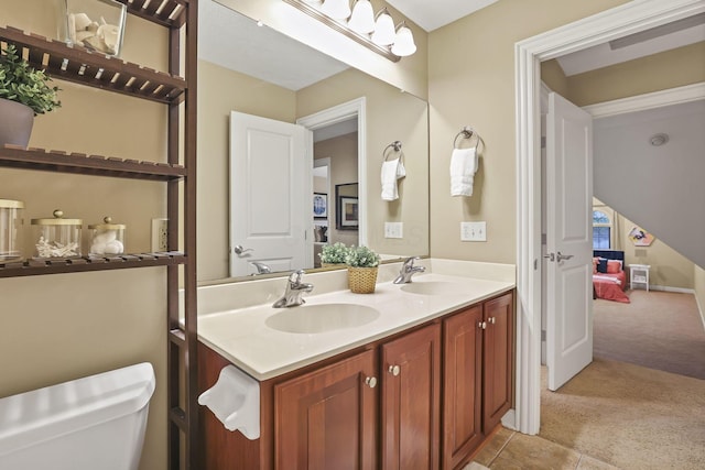 bathroom with a sink, toilet, and double vanity