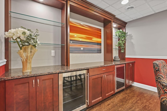 bar featuring dark wood-style flooring, beverage cooler, visible vents, and a dry bar