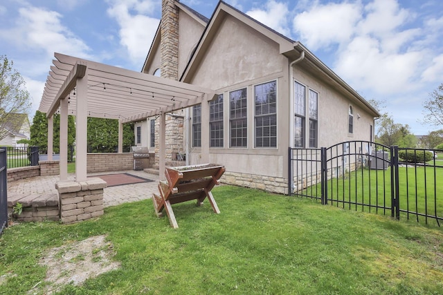 rear view of house featuring fence private yard, a pergola, stucco siding, an outdoor kitchen, and a lawn