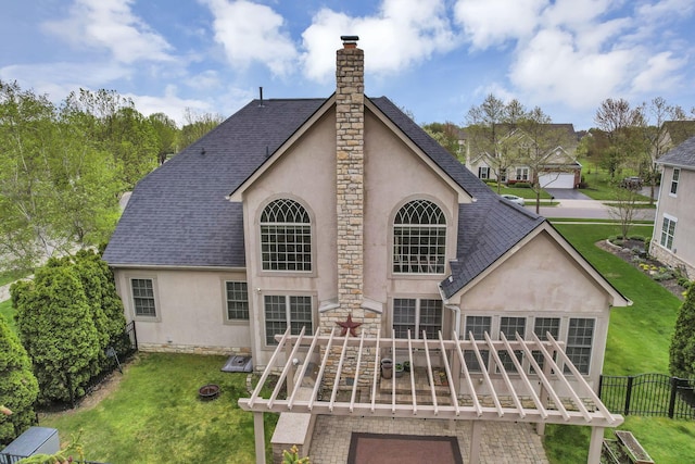back of house with fence, roof with shingles, stucco siding, a chimney, and a yard