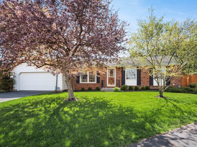 view of front of home with an attached garage, a front yard, brick siding, and aphalt driveway