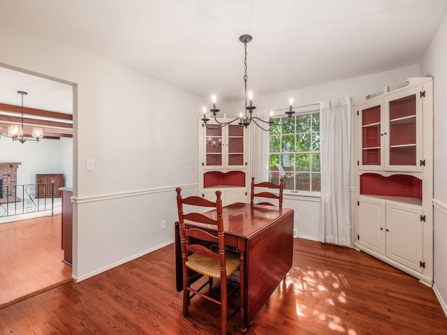 dining space featuring baseboards, wood finished floors, a notable chandelier, and a fireplace