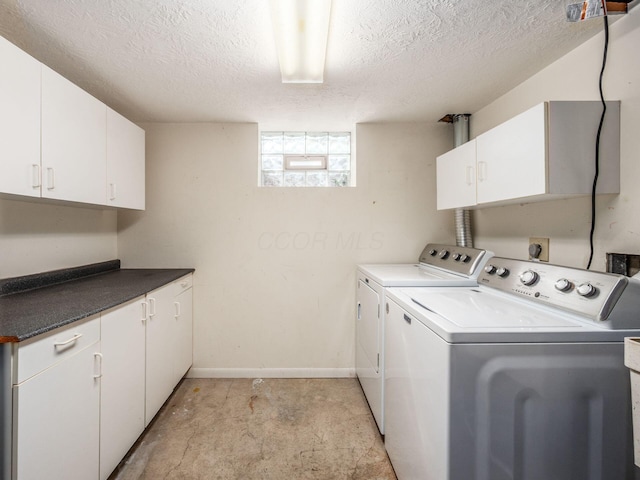 laundry area with cabinet space, a textured ceiling, baseboards, and washer and dryer
