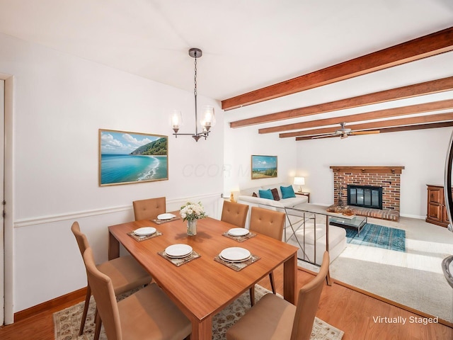 dining space featuring a brick fireplace, baseboards, a chandelier, and beamed ceiling