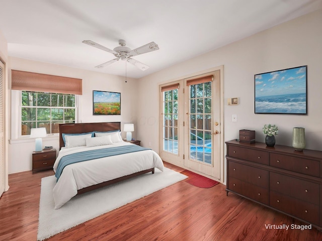 bedroom featuring access to outside, a ceiling fan, multiple windows, and wood finished floors
