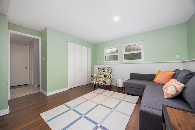 living room featuring a wainscoted wall, baseboards, and wood finished floors