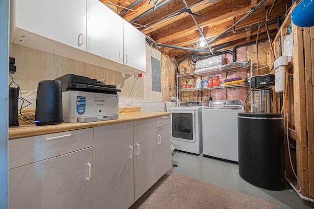 laundry area featuring separate washer and dryer, electric panel, and cabinet space