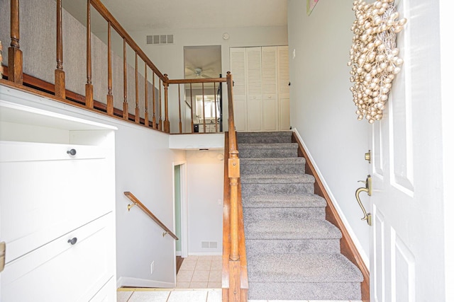 stairs featuring baseboards, a ceiling fan, tile patterned floors, and visible vents
