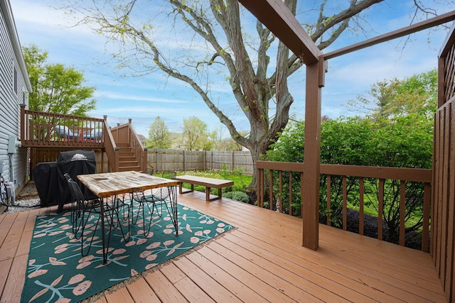 wooden terrace with a fenced backyard, stairs, and outdoor dining area