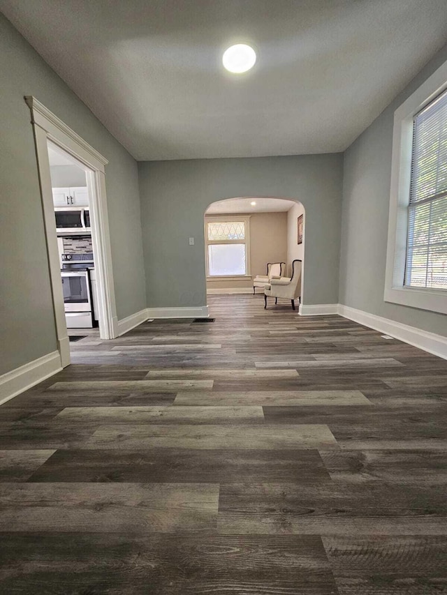 interior space with arched walkways, baseboards, and wood finished floors