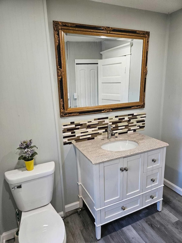 bathroom featuring vanity, wood finished floors, toilet, and tasteful backsplash