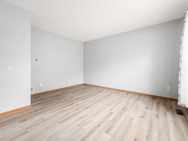 unfurnished room featuring baseboards, visible vents, and light wood-type flooring