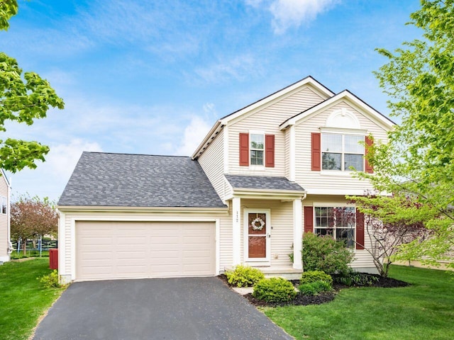 traditional-style home featuring an attached garage, a shingled roof, a front lawn, and driveway