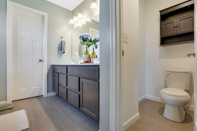 bathroom featuring baseboards, vanity, and toilet