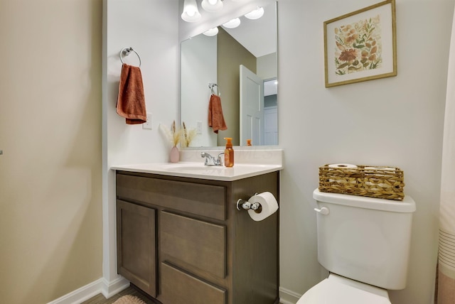 bathroom featuring vanity, baseboards, and toilet