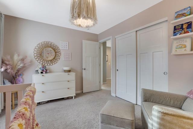 bedroom featuring baseboards, light carpet, a closet, and a notable chandelier