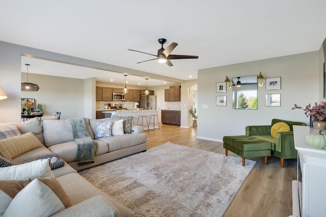 living room featuring light wood-type flooring, recessed lighting, baseboards, and ceiling fan