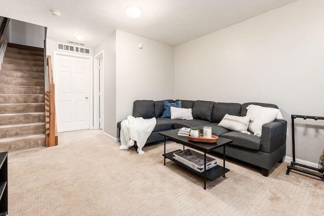 living room featuring a textured ceiling, visible vents, light colored carpet, baseboards, and stairs