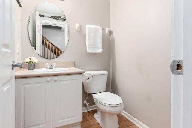 bathroom with toilet, baseboards, wood finished floors, and vanity