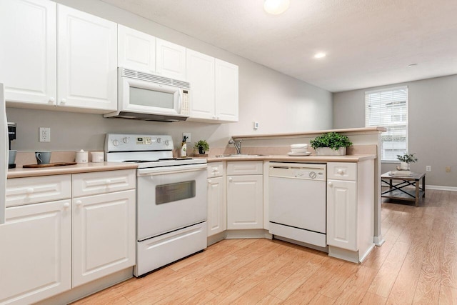 kitchen featuring light wood-style floors, white cabinets, a peninsula, and white appliances