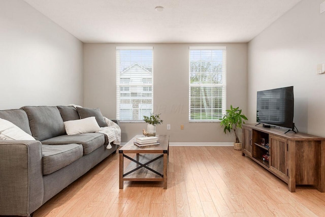 living area featuring baseboards and light wood finished floors