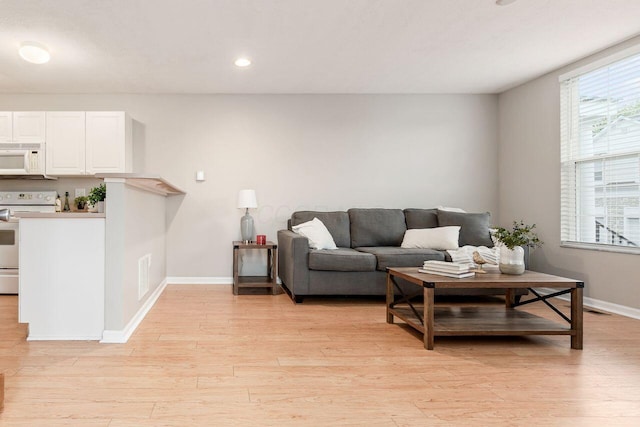 living room featuring recessed lighting, baseboards, visible vents, and light wood-style flooring