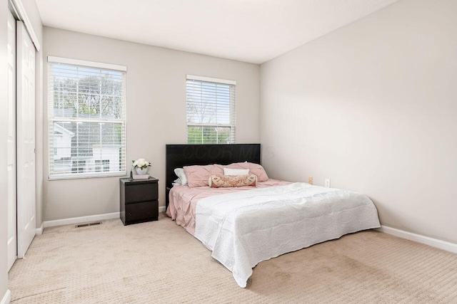bedroom featuring baseboards, light colored carpet, and multiple windows