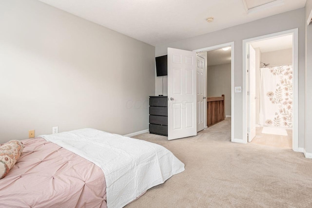 bedroom featuring connected bathroom, baseboards, and light carpet