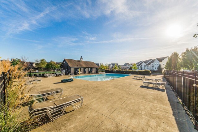 community pool with a patio area and fence