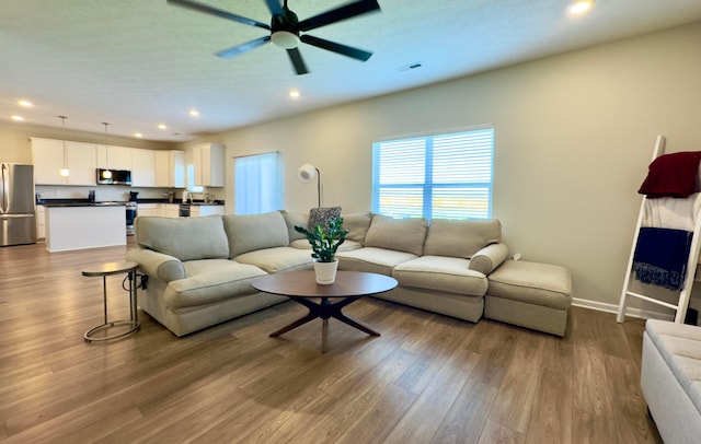 living area with a ceiling fan, visible vents, wood finished floors, and recessed lighting