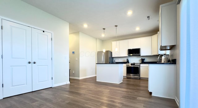 kitchen featuring a kitchen island, dark countertops, baseboards, recessed lighting, and stainless steel appliances