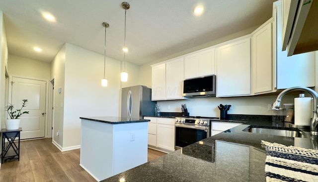 kitchen with wood finished floors, a center island, white cabinets, a sink, and stainless steel appliances