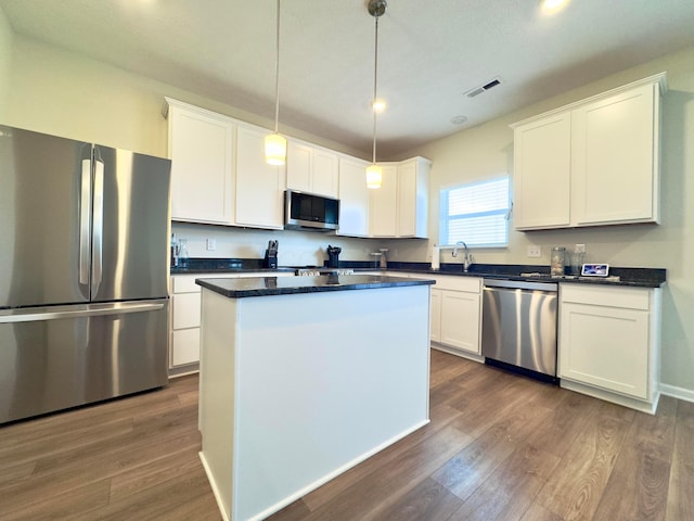 kitchen featuring dark countertops, stainless steel appliances, dark wood finished floors, and visible vents