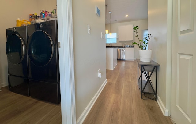 laundry area with independent washer and dryer, laundry area, a sink, and light wood-style flooring