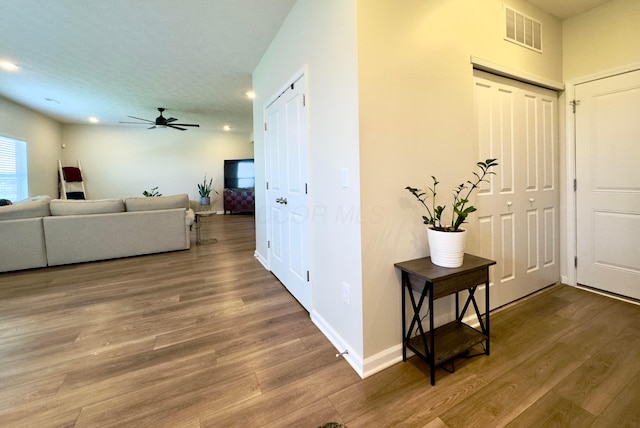 corridor featuring baseboards, recessed lighting, wood finished floors, and visible vents