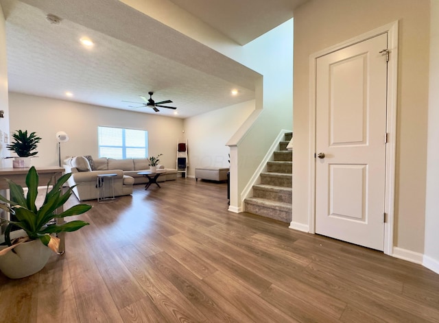 living area featuring a ceiling fan, stairs, wood finished floors, baseboards, and recessed lighting