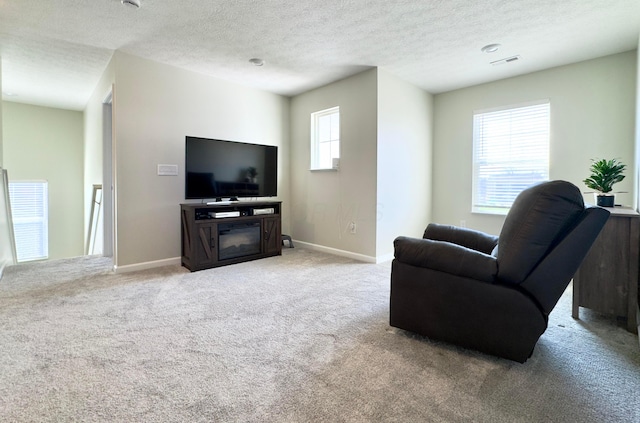 living room with baseboards, light carpet, a textured ceiling, and visible vents