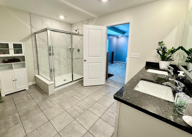full bath with a sink, a shower stall, and double vanity