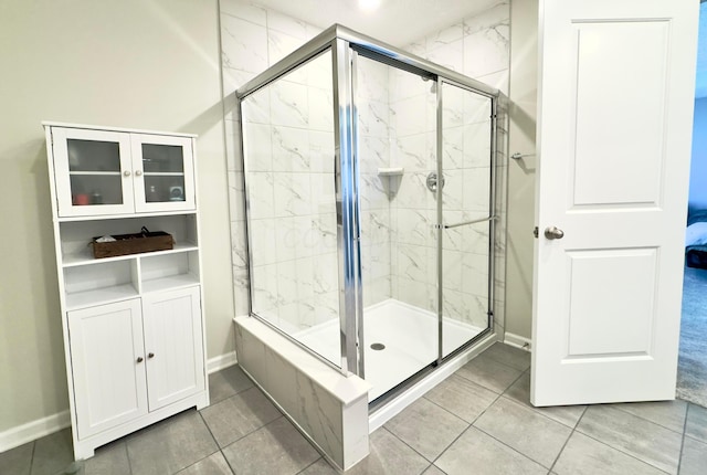 bathroom featuring baseboards, tile patterned flooring, and a shower stall