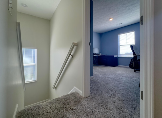 staircase featuring baseboards, carpet flooring, and a textured ceiling