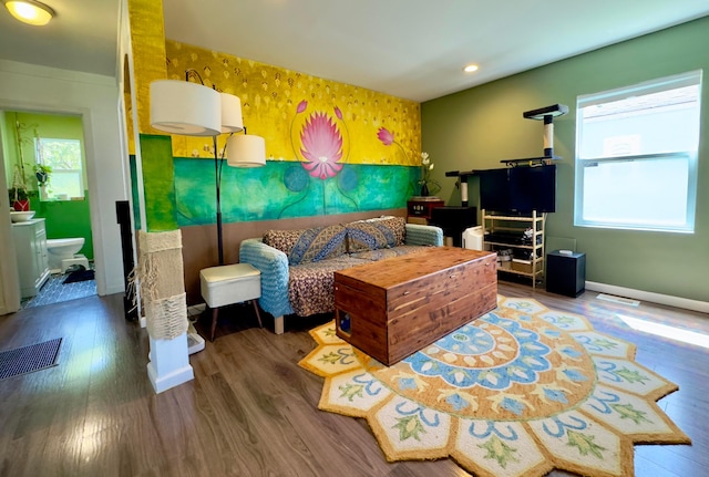 living room featuring baseboards, wallpapered walls, visible vents, and wood finished floors
