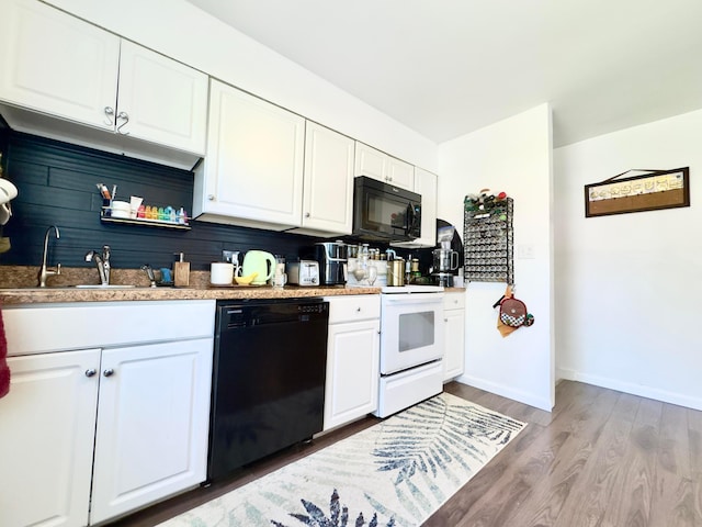 kitchen with baseboards, light wood-type flooring, white cabinets, a sink, and black appliances